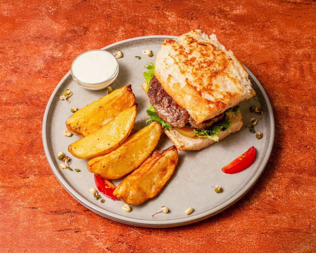 Gourmet burger with fresh greens and seasoned potato wedges