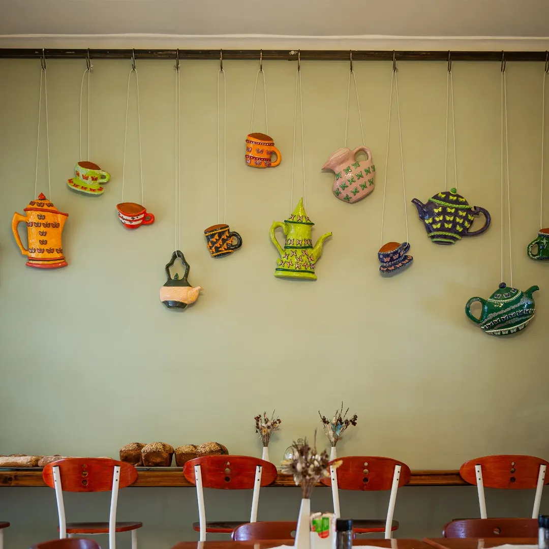 Colorful ceramic teapots and cups hanging as wall decoration